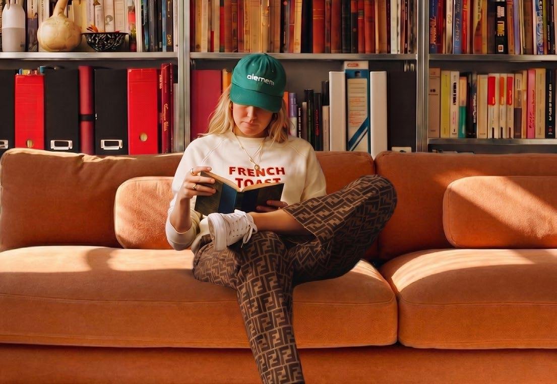 Raw District by Imtiaz Development - resident reading on an orange sofa in the library lounge